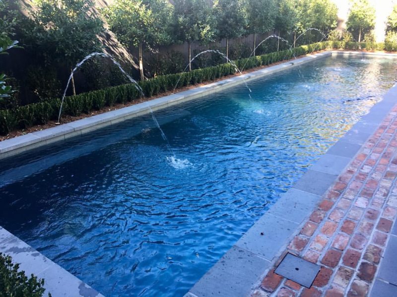 Arching deck jet lap pool with flagstone and brick decking in New